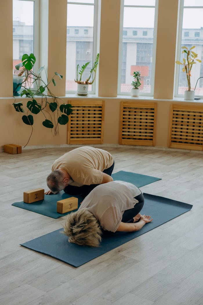 Two adults practicing yoga in a serene indoor setting, focusing on relaxation and wellness.